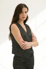 Chaleco grafito con cuello en V, cierre frontal con botones y bolsillos delanteros.