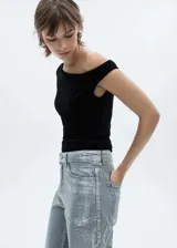 Top de terciopelo negro, de corte ajustado y diseño asimétrico con cuello barco y mangas asimétricas.