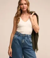 Blusa musculosa de punto color blanco, con escote en V y tirantes anchos.