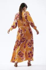 Vestido largo color naranja con estampado floral en tonos fucsia y blanco, escote en V y mangas largas.