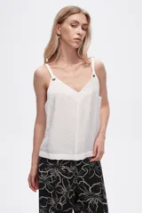 Musculosa blanca de bretel ancho con cuello en V y detalle de ojales metálicos en los tirantes. Corte al cuerpo.