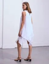 Vestido blanco de gasa con escote redondo bordado con apliques metálicos. Tiene forro interno a tono y ruedo en capas asimétricas.