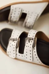 Sandalias marrones de cuero vacuno con doble tira y hebillas metálicas ajustables.