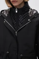 Campera negra con capucha, cordón ajustable en la cintura y cierre frontal con cremallera. Interior acolchado con estampado animal print.