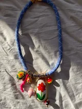 Collar con cordón azul y dijes de colores con forma de flor, cuentas y coral.