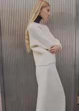 Sweater de punto grueso color blanco, con cuello redondo y mangas largas.
