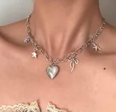 Collar plateado con cadena de eslabones y dijes colgantes: flor, estrella, corazón, moño y estrella de mar.