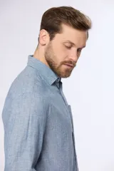 Camisa de lino color beige, de manga larga, con cuello clásico y bolsillo en el pecho.