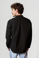 Camisa blanca de cuello mao y mangas 3/4 con botón para sujetar.