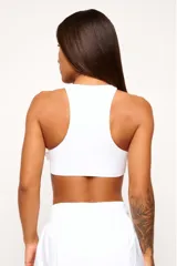 Top deportivo blanco de cuello alto, sin mangas y corte ajustado.