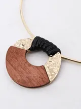 Gargantilla dorada con dije circular de madera y detalles en negro y dorado.