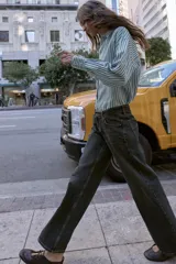 Jeans de tiro bajo, color negro lavado con efecto desgastado, corte de pierna ancha (wide leg) y cinco bolsillos.