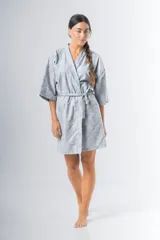 Bata kimono celeste con estampado floral, confeccionada en broderie de algodón, con mangas al codo y lazo de ajuste en la cintura.