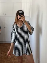 Vestido corto de tejido de punto a rayas horizontales blancas y negras, con escote en V y mangas cortas amplias.