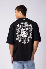Remera oversize blanca de algodón con un pequeño estampado circular en el pecho que simula un cerebro o un diseño abstracto en espiral, en color negro.