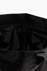Bolso de deporte negro de tela impermeable con doble asa de mano y correa de hombro ajustable. Tiene bolsillos laterales con cordón elástico y dos compartimentos interiores, uno con cierre y otro de malla.