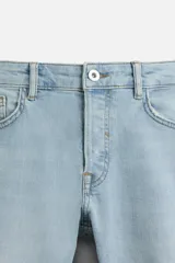 Pantalón de jean negro con corte skinny fit, cinco bolsillos, lavado con efecto roto y cierre frontal con cremallera y botón.