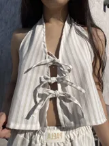 Top halter color beige con rayas verticales blancas y lazos ajustables en el frente y en la espalda.