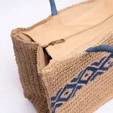 Bolso tipo tote de yute color beige con diseño geométrico azul y asas de soga azul.