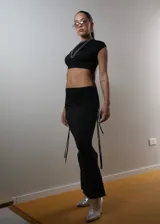 Conjunto de top corto negro de un solo hombro y falda larga negra con cordones laterales.