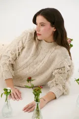 Sweater color arena de tejido de punto con cuello redondo y mangas largas con flecos.