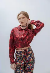 Camisa crop color bordó con estampado de flores grandes, cuello clásico, mangas largas con puños abotonados y lazos para atar en la cintura.