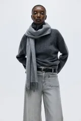 Pantalón de jean de tiro alto, color gris lavado, con pierna ancha y puños doblados. Presenta bolsillos de parche grandes en la parte delantera y bolsillos traseros.