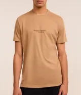 Remera color beige de algodón, corte comfort, con cuello redondo y mangas cortas. Presenta estampa de montañas y texto "Silence is louder in the wild".