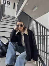 Campera negra de pana con cuello beige, cierre frontal y bolsillos laterales.