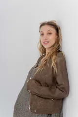 Chaqueta tipo biker de cuero ecológico (PU) color marrón con acabado desgastado, cuello Mao con broches metálicos, cierre frontal y bolsillos con cremallera.