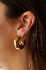 Aros en acero quirúrgico con acabado dorado y diseño en forma de dona.