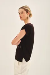 Remera negra de viscosa con calce suelto, escote redondo, manga corta y estampado frontal con bordado de lentejuelas doradas.