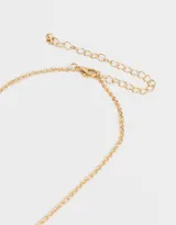 Collar corto dorado con cadena de eslabones y dijes colgantes: libélula, anillos y flor con centro de cristal rosado.