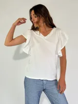Remera blanca de algodón con escote en V y mangas cortas con volados y detalle de puntilla.