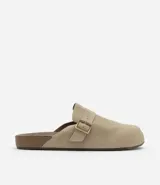 Ojota mule color beige confeccionada en cuero, con tira ancha y hebilla metálica.