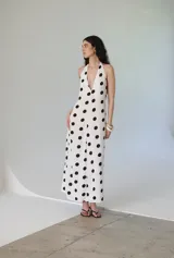 Vestido largo blanco con estampado de lunares negros, escote en V y espalda descubierta.