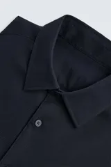 Camisa negra de manga larga con cuello italiano y cierre frontal de botonadura. Presenta un tejido con estructura de fácil cuidado.