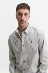 Camisa de manga larga gris oscuro, corte slim, con cartera abotonada, dos bolsillos frontales con botón y confeccionada en 100% algodón.