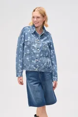 Campera de jean azul con estampado floral blanco, corte holgado, cuello camisero, cierre frontal con botones y bolsillos delanteros.