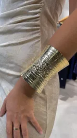 Brazalete dorado con diseño labrado.