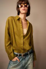Camisa de lino color verde oliva, con cuello solapa, manga larga con puños y cierre frontal con botones.