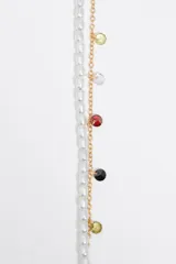 Pulsera doble con una hilera de perlas y otra de cadena dorada con cristales de colores.