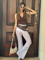 Pantalón acampanado de tejido de red calada con rayas verticales, cintura alta y corte ajustado.