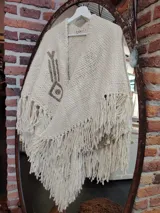 Ruana color crema tejida en lana merino con bordados a mano sobre lino.