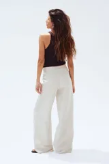 Pantalón sastrero color crema en tejido liviano de mezcla de lino y viscosa con pinzas adelante y atrás. Modelo de tiro alto con cierre, botón nacarado y piernas amplias.