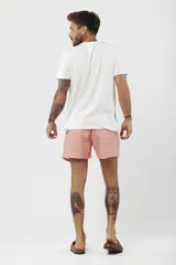 Short de baño con estampado de hojas de palmera en tonos beige, verde y naranja.