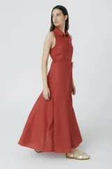 Vestido largo color ladrillo, sin mangas, con cuello camisero, cierre frontal con cremallera y lazo ajustable en la cintura.