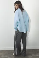 Pantalón de tiro alto negro a rayas verticales blancas, con cintura elástica ajustable con cordones, bolsillos delanteros y banda lateral blanca.