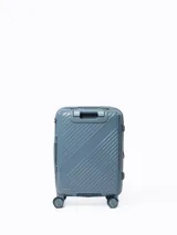 Valija rígida color celeste con diseño de líneas diagonales en el frente. Tiene manija retráctil superior, manija lateral, cuatro ruedas con giro de 360° y candado de seguridad.