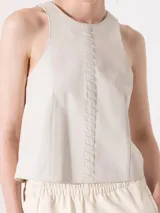 Top sin mangas de cuero color blanco roto, con cuello redondo y detalle de trenzado vertical en el centro del pecho.